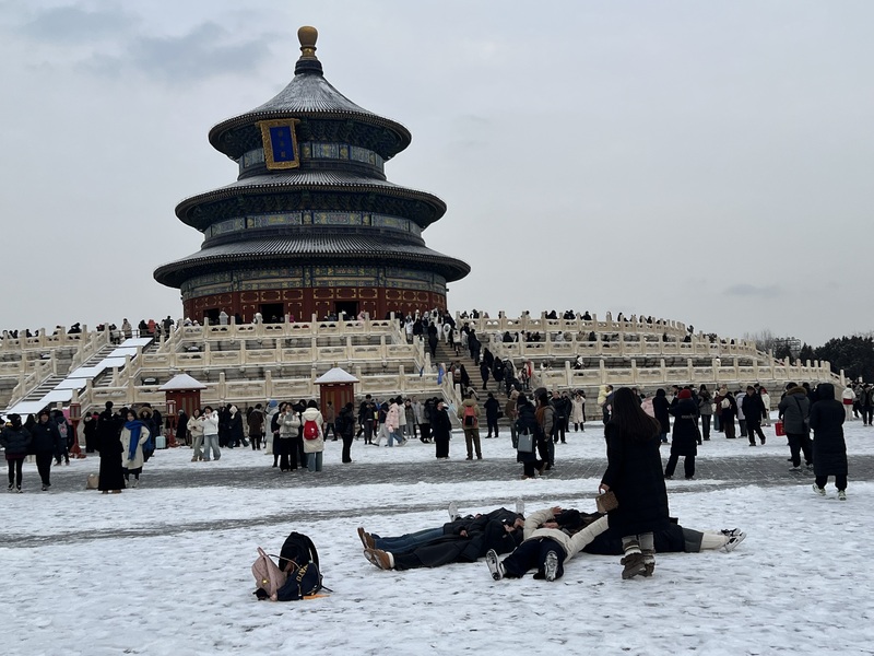 北京17日晚間下起2026年首場雪，圖為18日北京天壇的遊客把 握北京難得的下雪時光，躺在地上盡享古韻冬景。 中央社記者呂佳蓉北京攝 115年1月18日