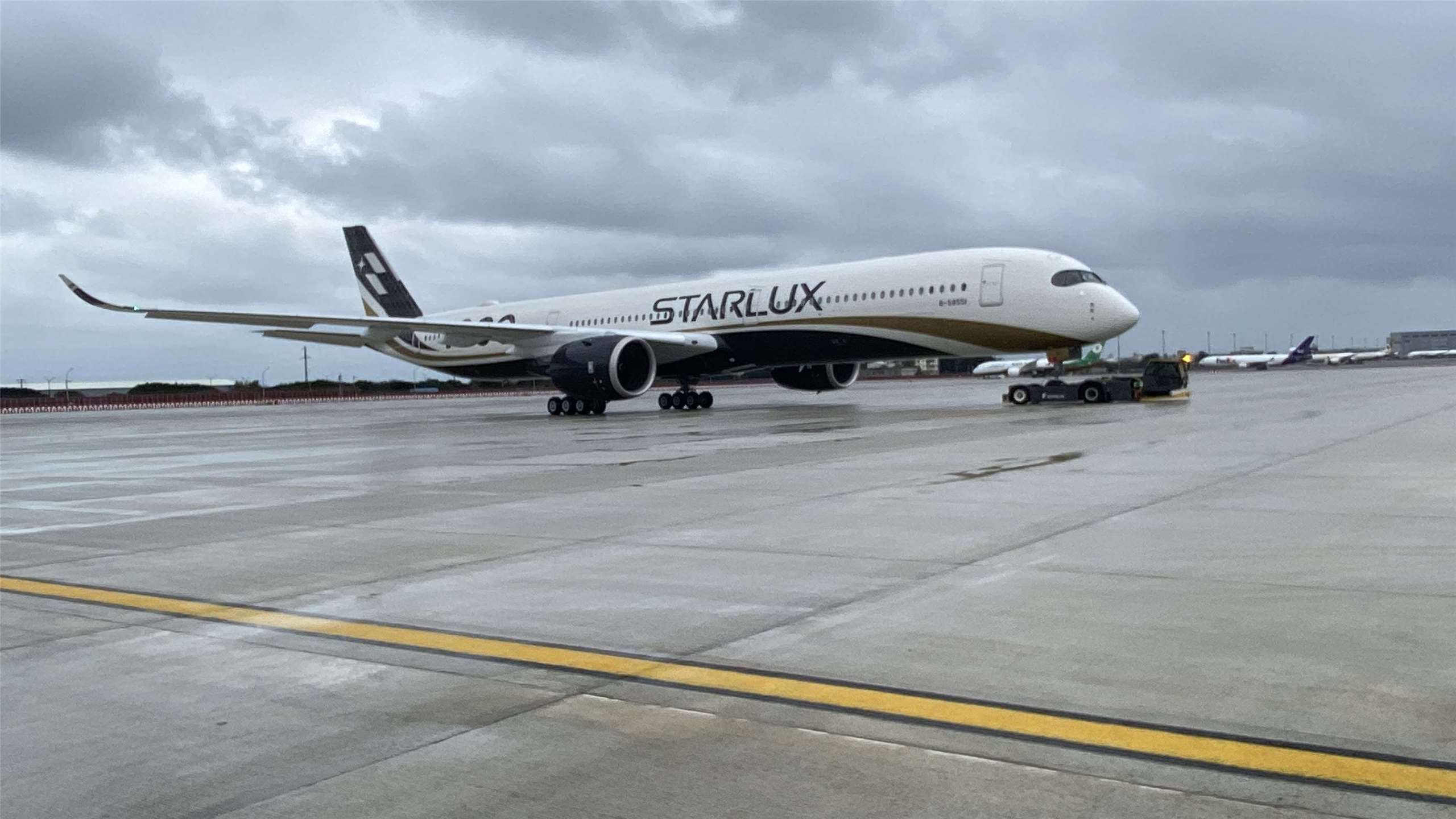 星宇航空全新引進的全台首架A350-1000廣體客機21日示範在拖機帶領下緩緩停靠在第三跑道臨時過夜機坪的過程。 (吳琍君 攝)