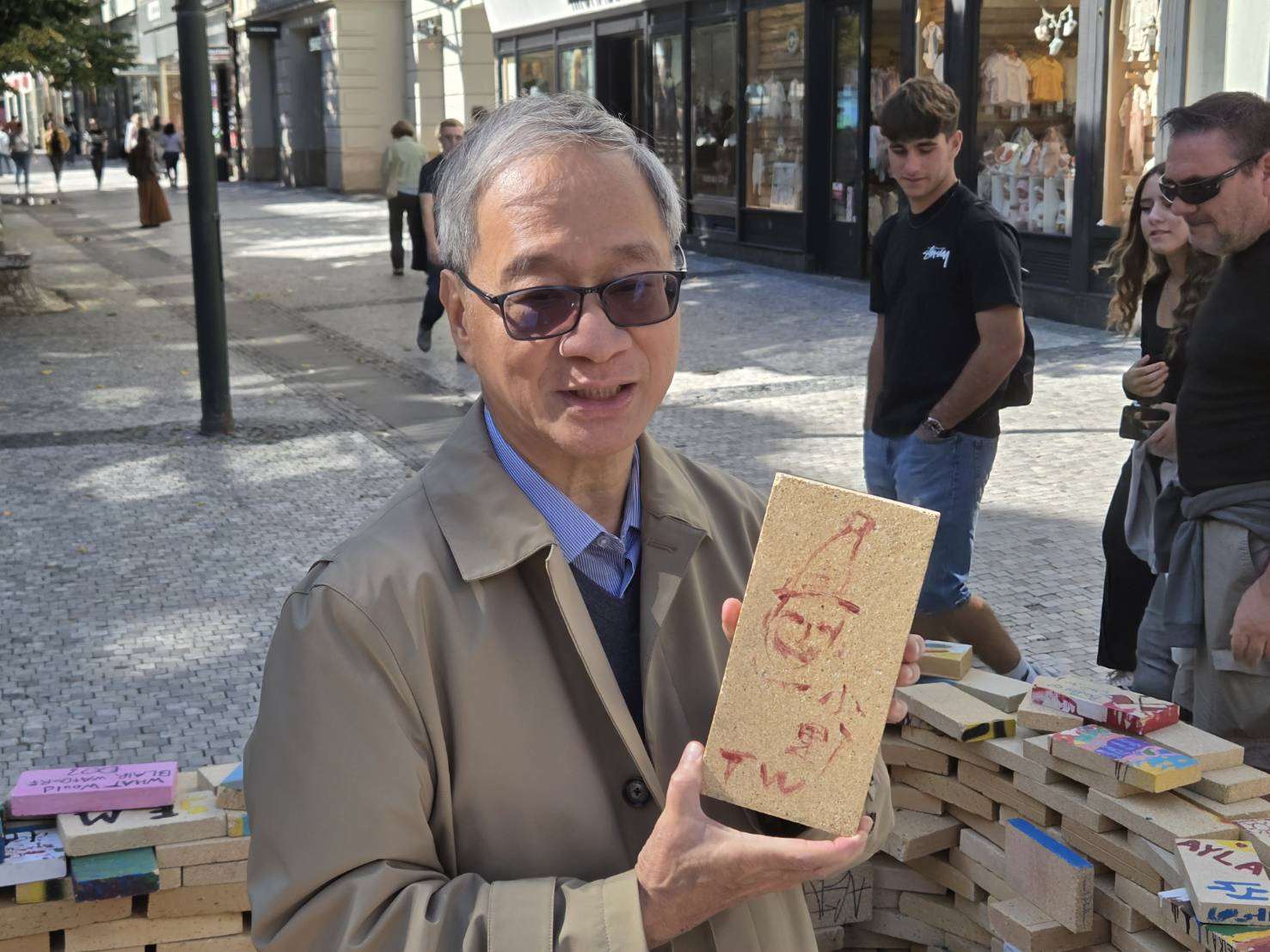 李遠童心一來在布拉格街頭行動藝術裝置上也留下一幅逗趣的自畫像,還簽上「小野」與代表台灣的「TW」。(江昭倫 攝)