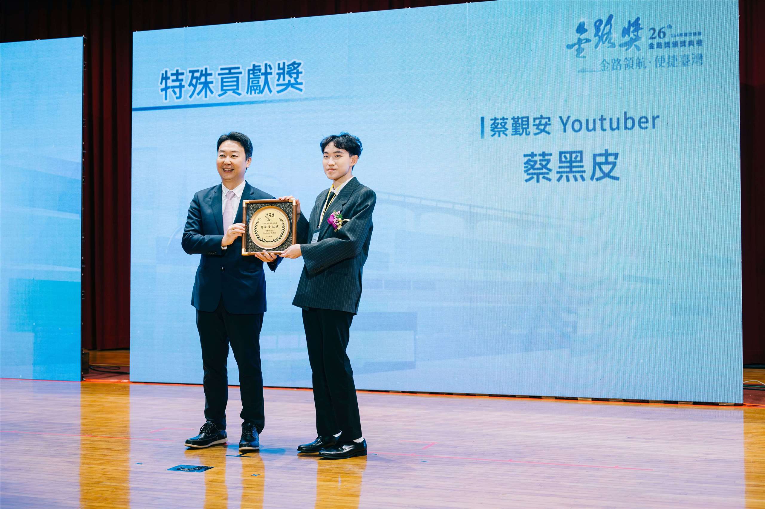 本名蔡覲安的Youtuber蔡黑皮(右)12日從交通部長陳世凱手中領取今年度的「金路獎-特殊貢獻獎」。(交通部提供)