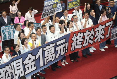 The special budget passed after the third reading on Friday, October 17, 2025. KMT legislators were seen cheering, while some legislators held banners reading "Universal cash handout of NT$10,000! Finally!" (Photo: CNA)