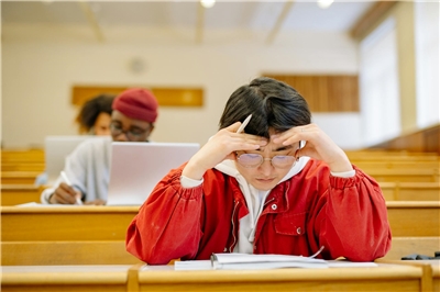 A man in a red jacket studying in a classroom. (Photo: pexels)