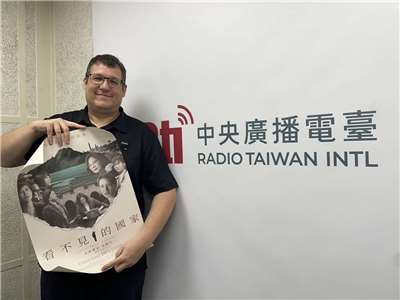 Michael Geier in the Rti studio with a poster for his film, "Invisible Nation".  (Photo: Lisa Duffaud）