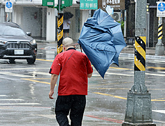 Strong winds blew an umbrella off a person in New Taipei City while he was out on October 23. (Photo: CNA)