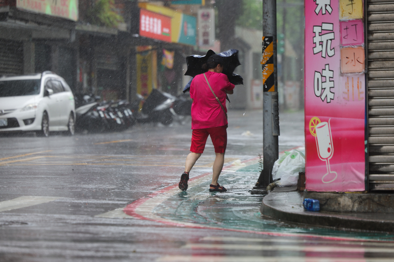 As Bavi hit Taiwan on July 11, a resident in Taipei could not open her umbrella due to the strong wind. (Photo: CNA)