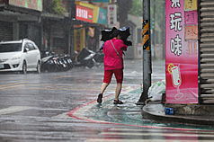 As Bavi hit Taiwan on July 11, a resident in Taipei could not open her umbrella due to the strong wind. (Photo: CNA)