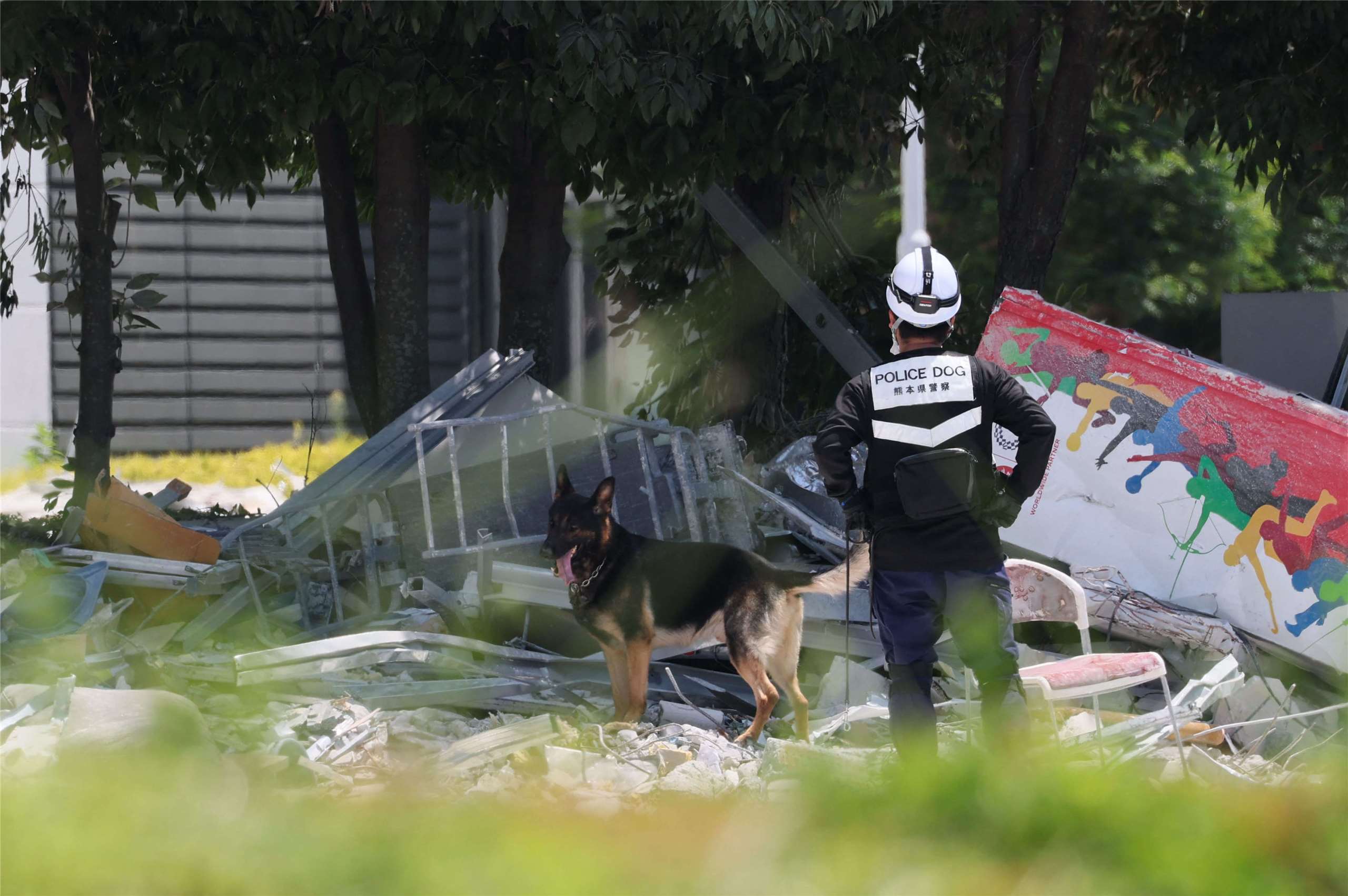 A police dog and police officer searching the wreckage of the AEON Mall in Kumamoto. (Photo: AFP)