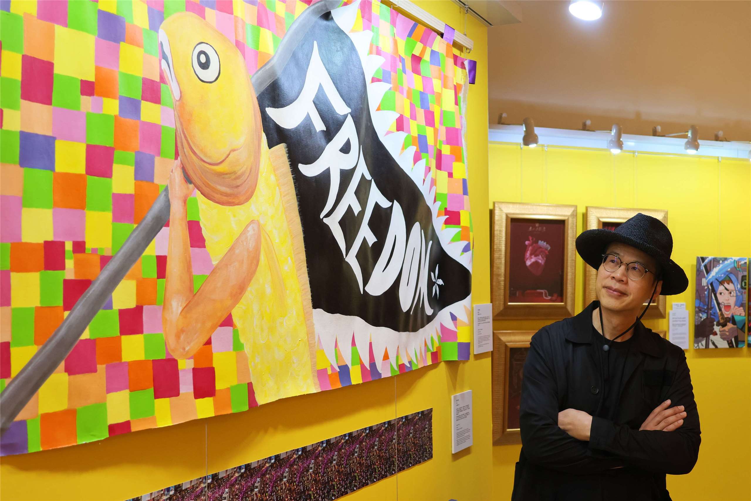 Hong Kong artist and exhibition curator Kacey Wong stands beside artwork at the third Hong Kong Human Rights Art Exhibition in Taipei on June 10, 2026. (Rti Photo/James Thompson)