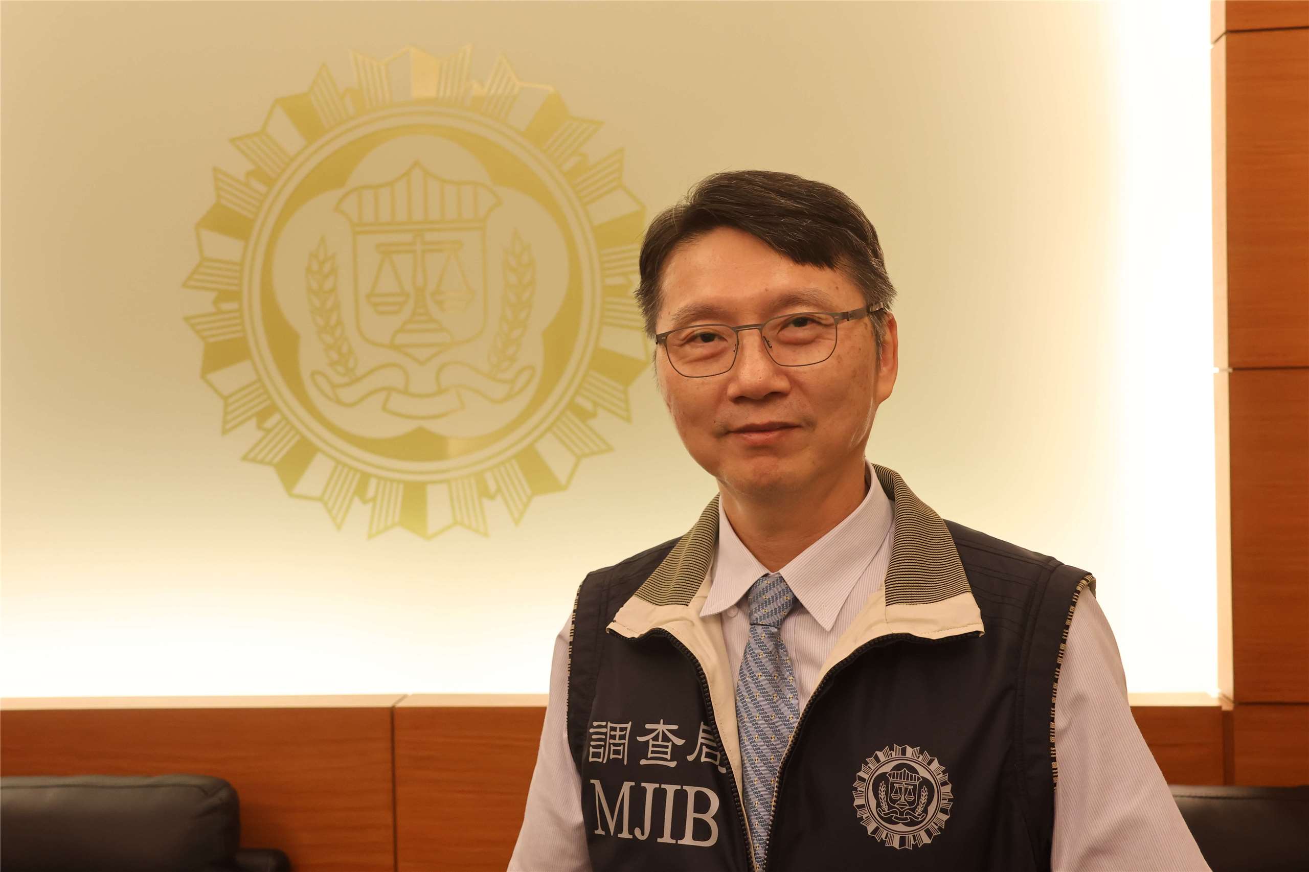 Drug Enforcement Division Section Chief Li Jia-ning stands in front of the MJIB logo following an interview with Rti in Taipei on July 6, 2026. (Rti Photo/James Thompson)