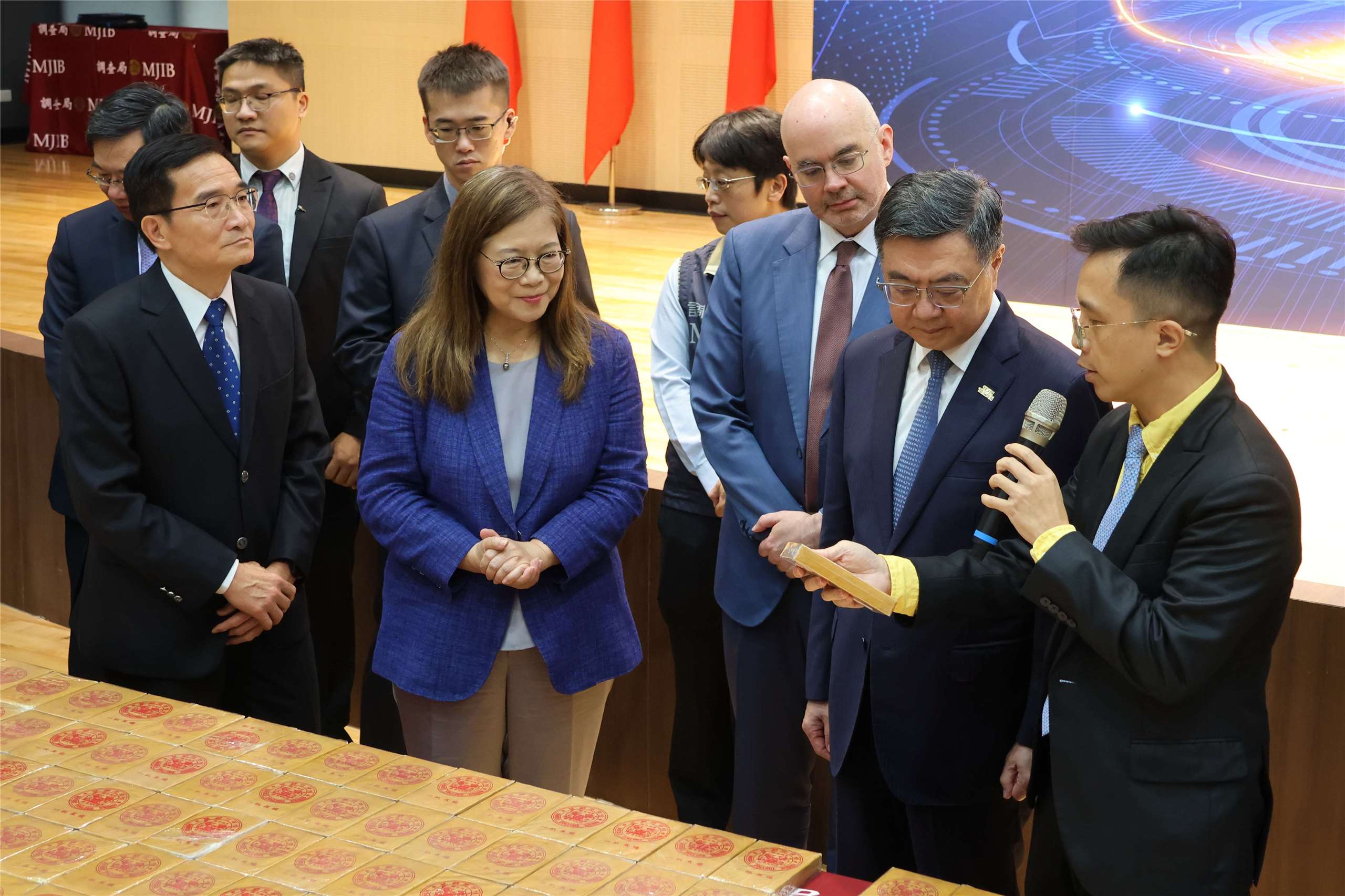 Prosecutor Justin Lai shows a seized drug package to officials including Premier Cho Jung-tai and AIT Director Raymond Greene at a news conference in New Taipei City on June 16, 2026. (Rti Photo/James Thompson)