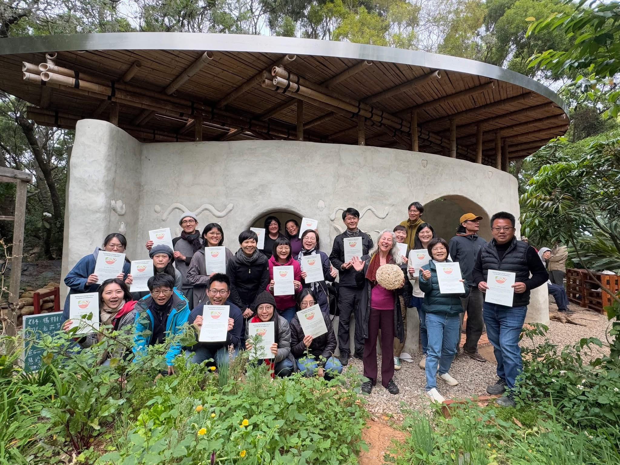 Photo finale du cours de design en permaculture 2024 par Tammy Turner à l'Association d'éducation à l'agriculture urbaine de Taichung, devant la Maison Goutte, construction en terre, chaux et bambou (photo : FB de 臺中市食農教育發展協會)