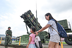 Une mère et ses enfants passent devant des militaires à Taipei
