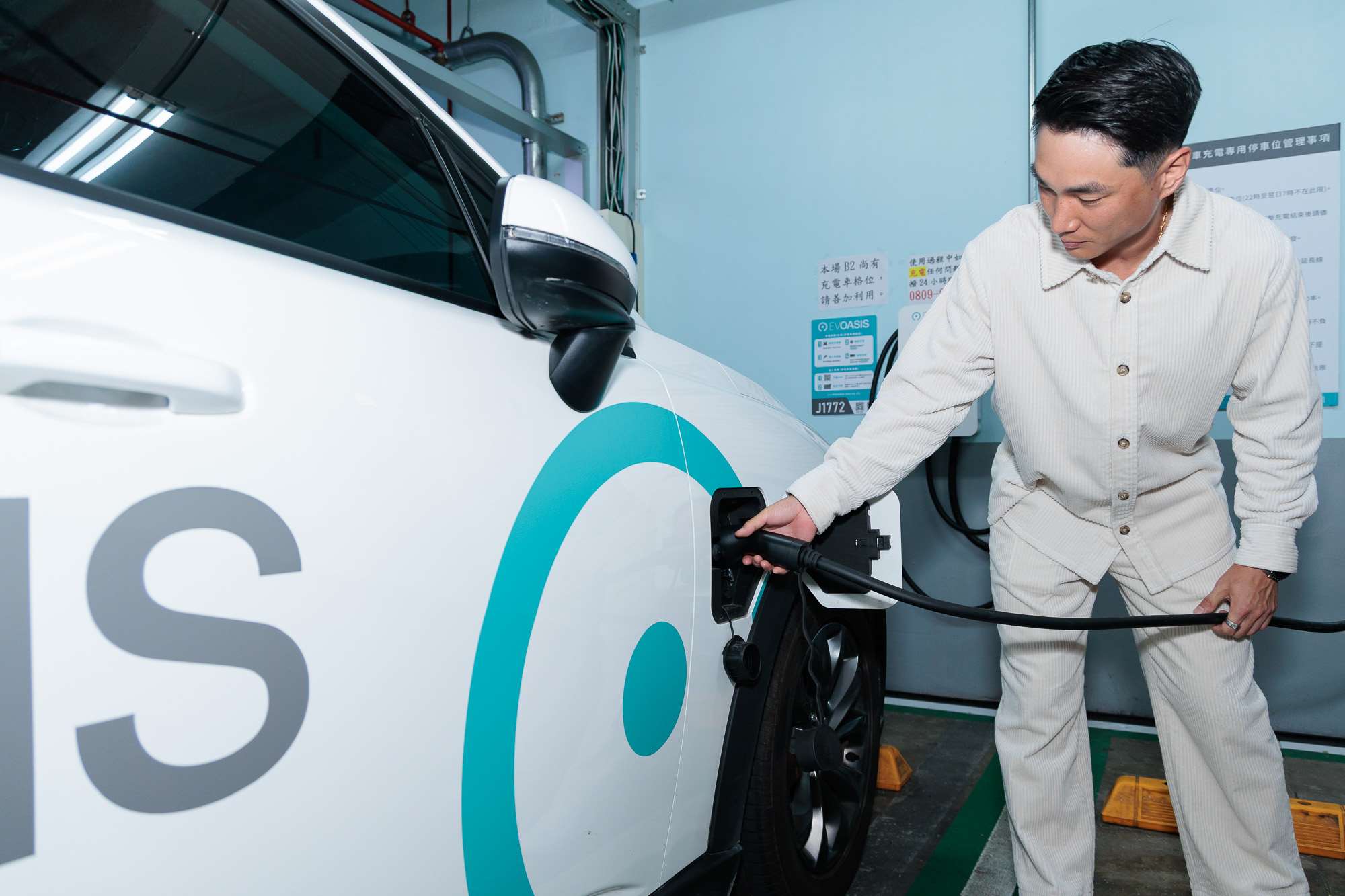 Calvin Chen, fondateur d'EVOASIS chargeant une voiture électrique (photo FB EVOASIS)