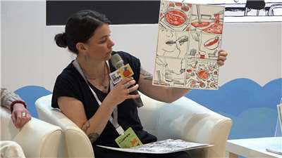Emy montre une planche originale de la bande dessinée "Femmes, soutiens-gorges et pattes de poulet" au Salon du Livre (photo Rti)