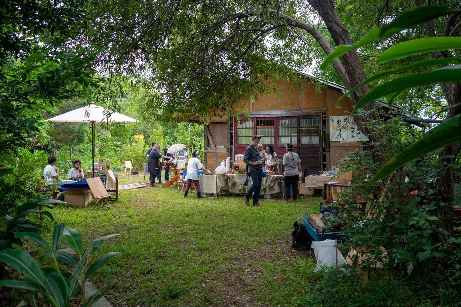 Un marché à Worldwide Open Studio à Taoyuan, avec en arrière plan, la maison en terre, bambou et bois qui accueille notamment des conférences ou autres activités (photo : Sasa)