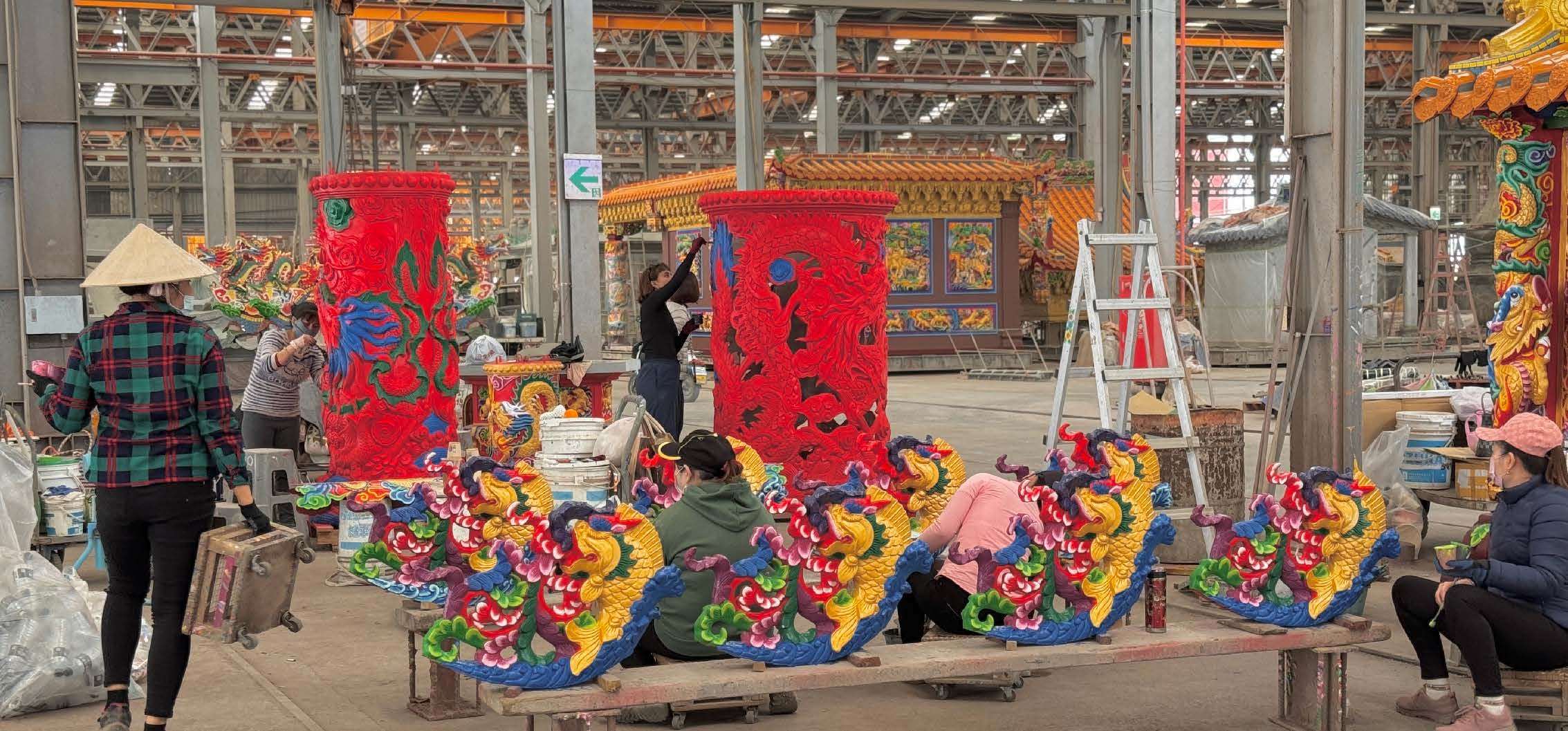 Usine de fabrication de temples modulaires ; Inès, debout au centre, est en train de peindre un pilier de temple (photo transmise par Inès Minfray)