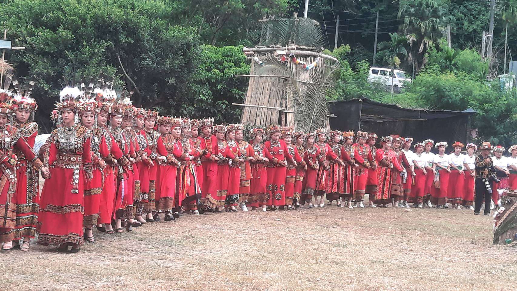 Jeunes filles avec une coiffe ornée de plumes devant, sans plumes ensuite et avec un T-shirt blanc à l'arrière : les différences de classe sociale et de classe d'âge sont marquées dans les vêtements et les parures (cérémonie des récoltes de Taromak, Rti)