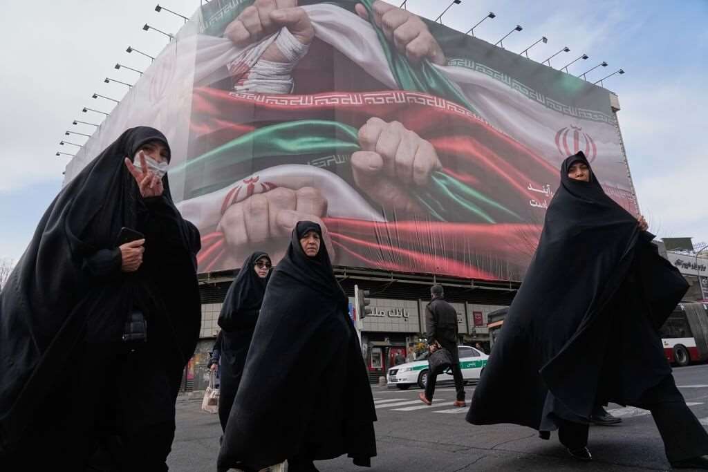 Keterangan foto: sekelompok wanita Iran berjalan melewati papan reklame besar di Teheran (foto: AP)