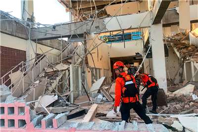 Petugas penyelamat sedang bekerja di tengah reruntuhan bangunan yang rusak akibat gempa bumi di Maumere, Provinsi Nusa Tenggara Timur. (Foto: AFP)