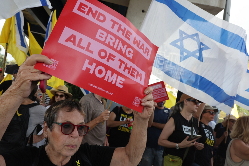 Humahawak ng mga plakard at bandila ng Israel ang mga nagpoprotesta sa isang kilos-protesta na inorganisa ng mga pamilya ng mga bihag na Israeli. Ang mga bihag ay hawak sa Gaza Strip mula Oktubre 2023, at nananawagan ang kanilang mga pamilya ng agarang aksyon upang matiyak ang kanilang pagpapalaya, pati na rin ng tigil-putukan sa digmaan laban sa Hamas. Ginawa ang protesta noong Agosto 26 sa Tel Aviv. Photo from AFP.