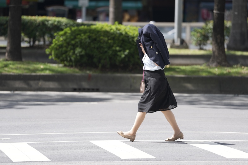 近期受太平洋高壓影響，各地晴朗炎熱。圖為3日台北市中正區民眾以衣物遮擋豔陽。
