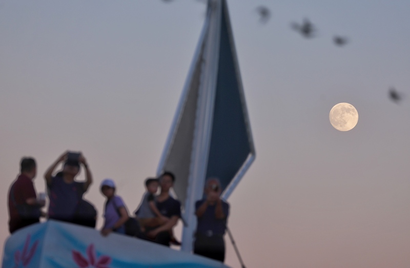 中秋節好天氣　各地賞月機會高。圖為台北大佳河濱公園傍晚已可見明月高掛，出遊民眾開心同賞夕陽與月亮。