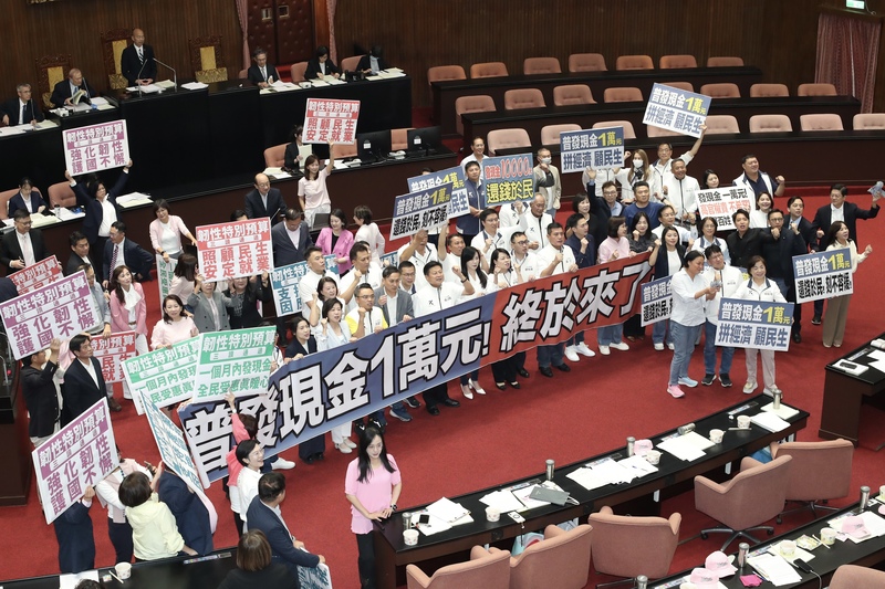 立法院會17日三讀通過「中央政府因應國際情勢強化
經濟社會及民生國安韌性特別預算案」，其中包含普
發現金1萬元預算新台幣2360億元。圖為朝野立委在
議場內拿著手舉牌呼口號。(資料照片)
