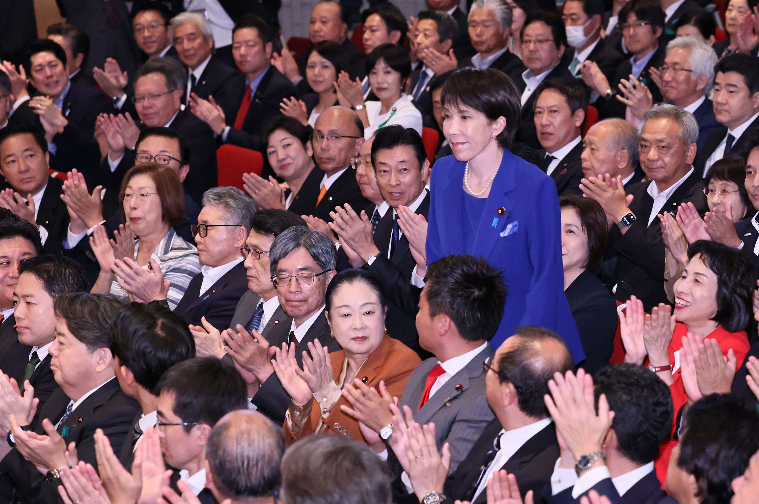 高市早苗在贏得自民黨總裁選舉後，起立致意。
