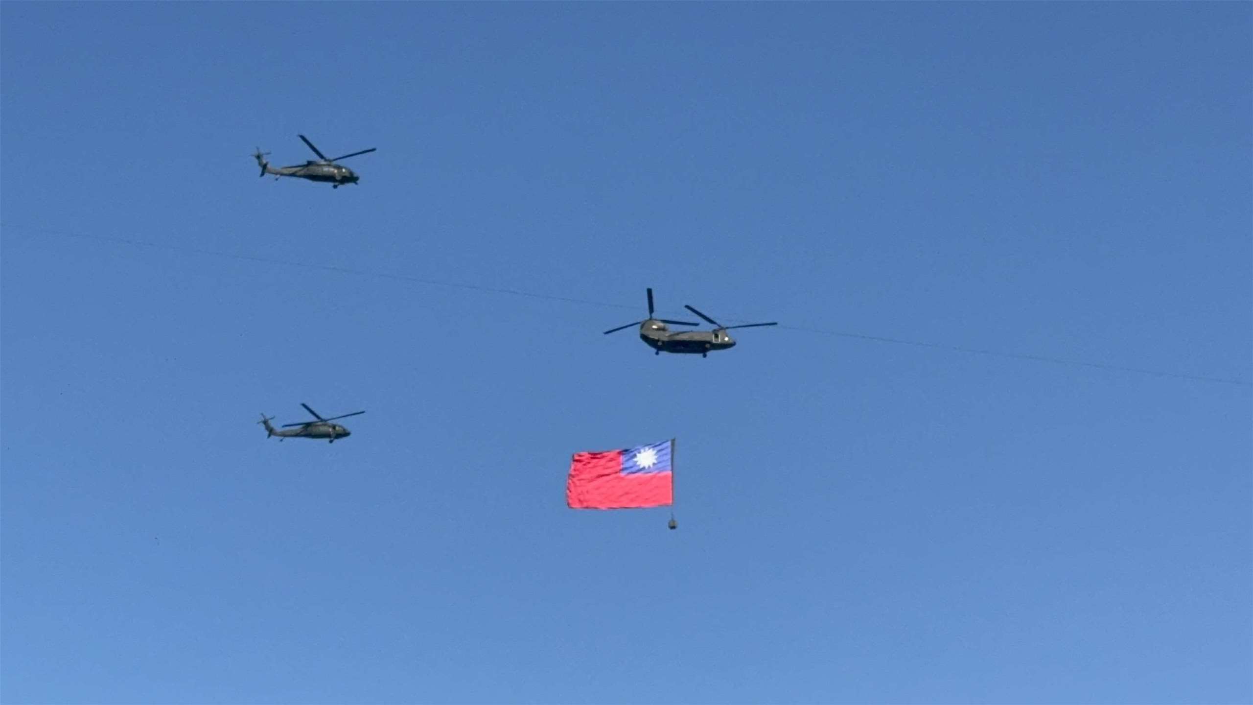 114年國慶大會6日下午順利完成預演，在唱國歌階段，由黑鷹直升機伴隨護衛契努克運輸直升機吊掛巨幅國旗，飛越觀禮台。(謝佳興 攝)