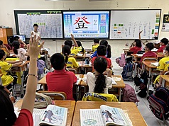 越南胡志明市台灣學校課程、師資、教材皆與台灣同步，彷彿置身台灣，幾年前也引進電子互動白板，方便又環保。老師正在台上帶著孩童一筆一畫書寫正體國字與注音。