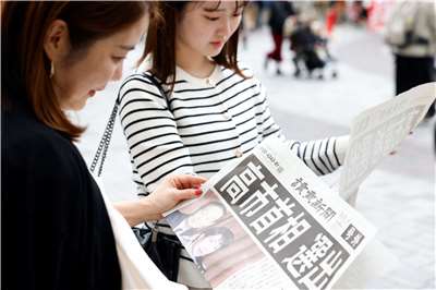 日本自民黨總裁高市早苗21日被國會指名為日本第104任首相後，民眾在街頭爭讀報紙快報。(路透社/達志影像)