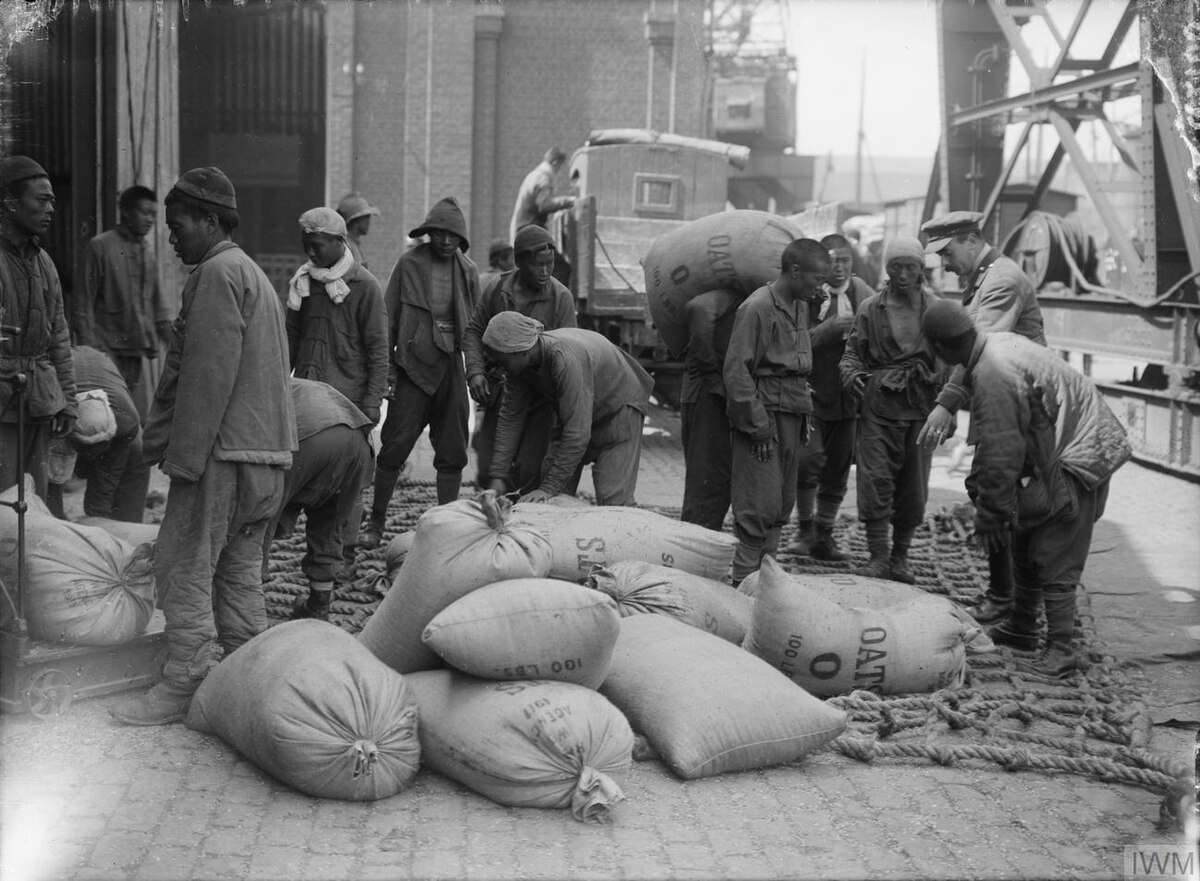 華工在英軍軍官的監督下將一袋袋的燕麥裝車。1917年8月12日攝於濱海布洛涅。(圖：公有領域)