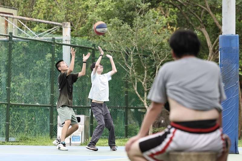 把握週末好天氣，台北市南港區民眾於球場打球，場邊民眾拉起衣服散熱。(資料照片)