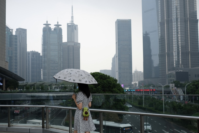 中國通貨緊縮問題持續蔓延，企業流血競爭，形成虧損倒閉層出不窮，受薪階級面臨失業壓力，降低消費意願的情況比預期還嚴重，加上中國仍努力生產，恐將通縮壓力擴及貿易夥伴。圖為上海陸家嘴天橋上撐傘的路人。