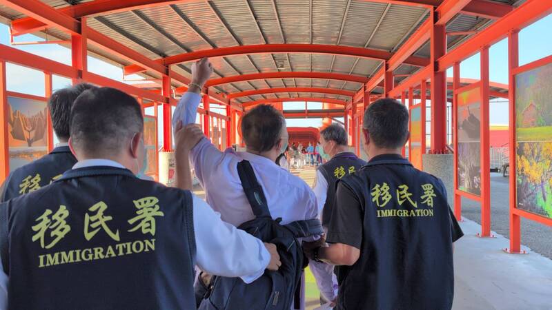 盧姓中國籍男子（舉手者）6日在金門縣政府前拋撒寫有「統一台灣」等字句傳單，遭強制驅逐出境。移民署人員將盧男帶往小三通碼頭途中，他還數度高喊「兩岸和平統一」、「打倒台獨」等語。 (圖：中央社)