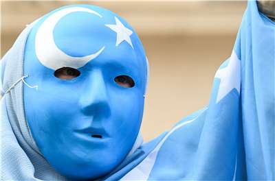 法國下薩克森州政府將一名維吾爾女子遣返中國引發爭議。圖為一名戴著印有維吾爾族旗幟口罩的抗議者。示意圖 (AFP)