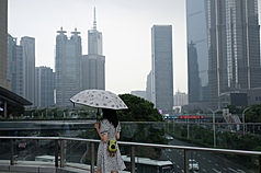 中國通貨緊縮問題持續蔓延，企業流血競爭，形成虧損倒閉層出不窮，受薪階級面臨失業壓力，降低消費意願的情況比預期還嚴重，加上中國仍努力生產，恐將通縮壓力擴及貿易夥伴。圖為上海陸家嘴天橋上撐傘的路人。