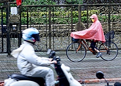 氣象署表示，未來一週天氣先潮濕後穩定，後半週各地有機會見到陽光。圖為台北市萬華區民眾2日穿雨衣擋雨。
