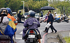 颱風鳳凰接近台灣，在高雄市新興區，民眾撐傘過馬路。
