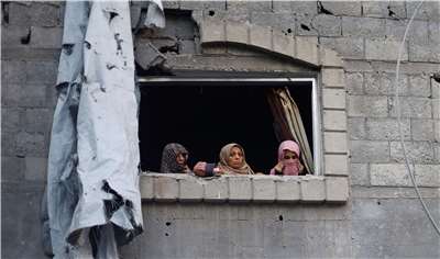 巴勒斯坦婦女從加薩走廊遭以色列空襲地點附近的窗戶向外張望。