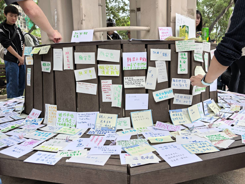 香港宏福苑26日發生奪命大火，民間在悲痛中自發支援、呼籲徹查原因與責任。圖為市民在大火附近公園的坐椅貼上悼念卡。