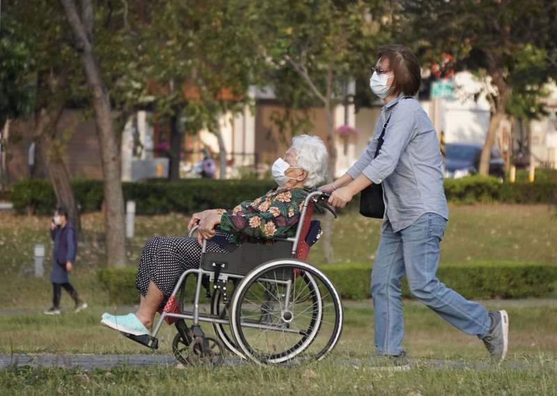 圖為民眾為長者推著輪椅到高雄市鳳山區公園內散心。資料照。