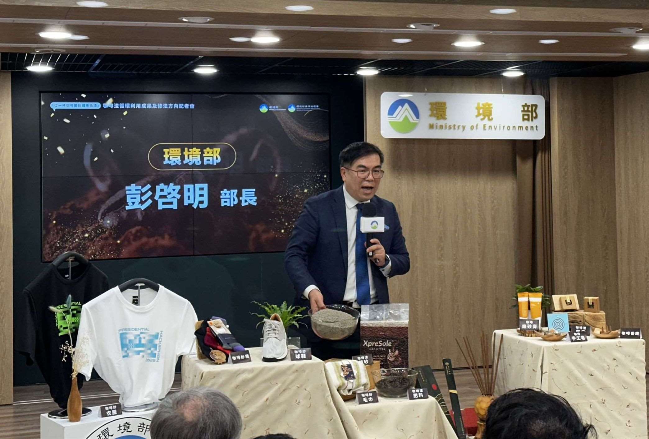 環境部長彭啓明說明咖啡渣可以做成非常多商品，像是他手中拿的貓砂也很好用。(楊雨青攝)