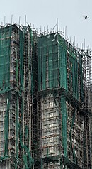 香港大埔宏福苑大火慘劇發生後，由於有證據顯示部分棚網在阻燃檢測方面有造假情況，港府勒令所有在維修之中的大樓棚網全部下架；圖為宏福苑在大火後殘存的棚網。