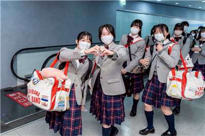 「橘色惡魔」日本京都橘高校吹奏樂部學生們看到熱情接機人士及媒體相當開心，頻朝鏡頭揮手或比愛心手勢。(圖：文化總會臉書)