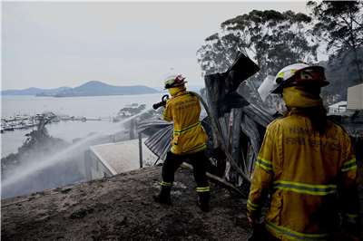 澳洲東南部地區最近爆發大規模野火，造成許多房屋與土地被焚毀。圖為當地消防人員進行灌救。(路透社/達志影像)