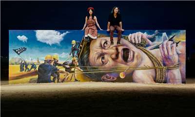 流亡倫敦的香港藝術家夫妻檔「淋漓淋浪」在美國自由雕塑公園完成巨幅壁畫，兩人坐在壁畫上，顯得渺小。(淋漓淋浪提供)