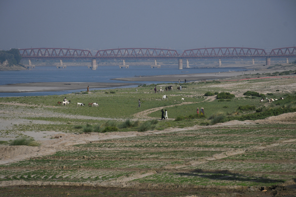 人們走在印度河乾涸河床上的耕地旁。攝於巴基斯坦海德拉巴(Hyderabad)。