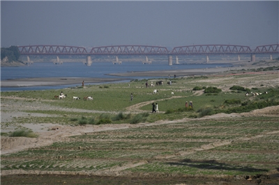 人們走在印度河乾涸河床上的耕地旁。攝於巴基斯坦海德拉巴(Hyderabad)。