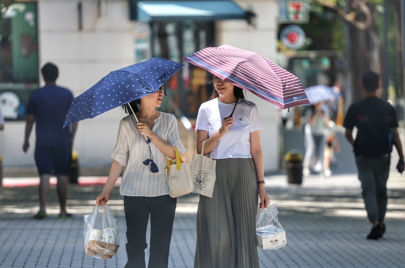 圖為外出的上班族撐傘遮擋陽光。資料照。
